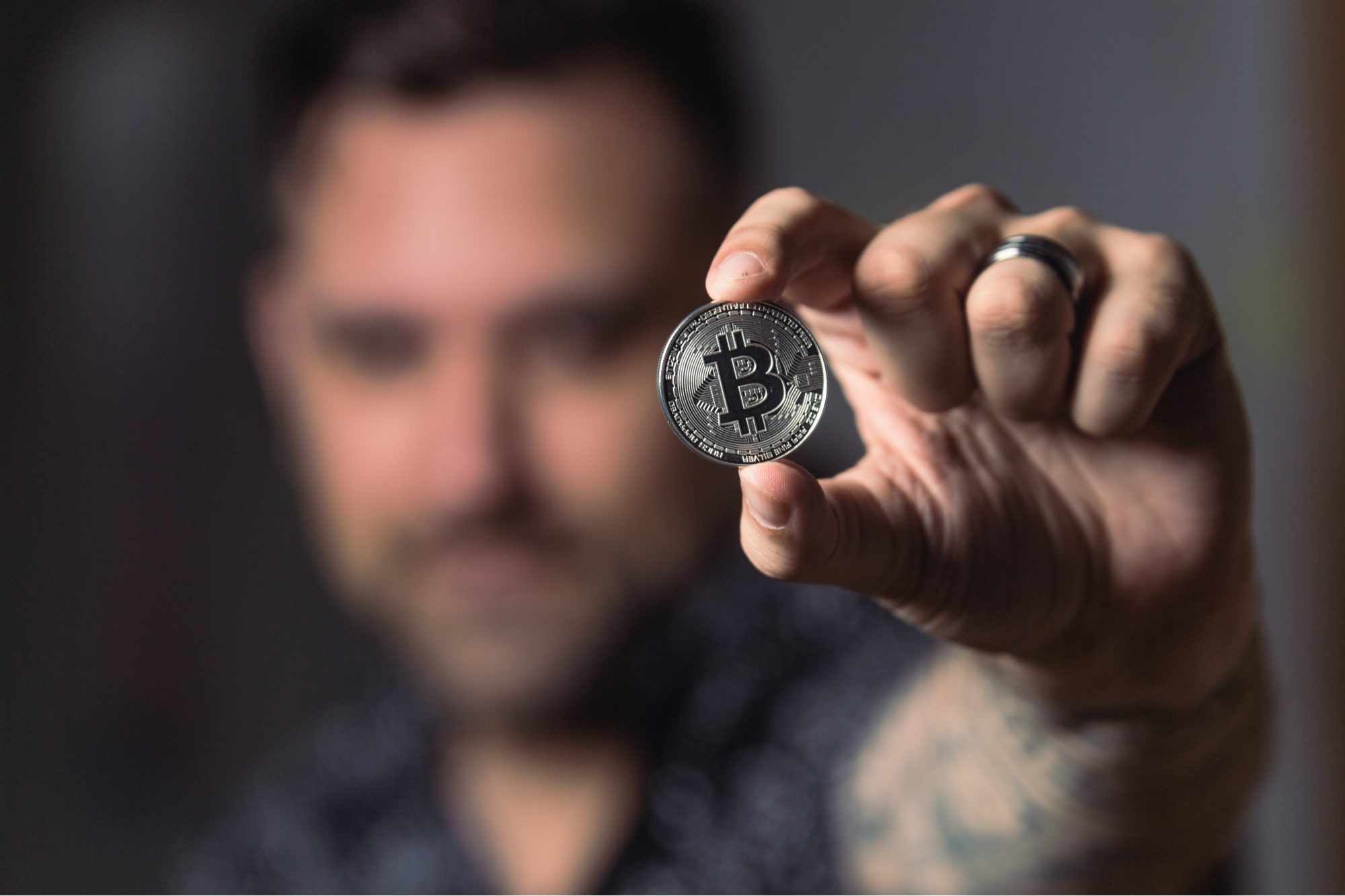 Photo of man holding a bitcoin